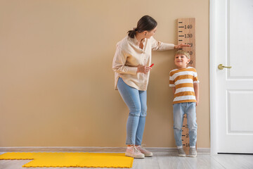 Little boy with nanny measuring height at home - obrazy, fototapety, plakaty