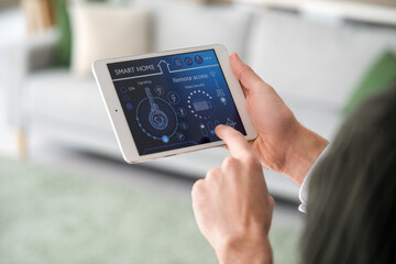 Young man using smart home security system control panel, closeup