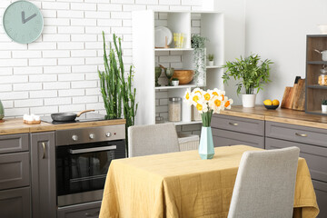 Interior of modern kitchen with blooming narcissus flowers in vase on table