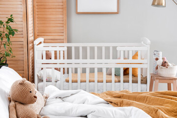Baby crib in interior of light bedroom