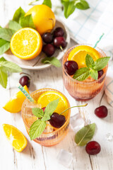 Fototapeta premium Iced refreshment drink orange cherry cola lemonade or mojito cocktail in glass on a wooden table. Fresh summer drink.