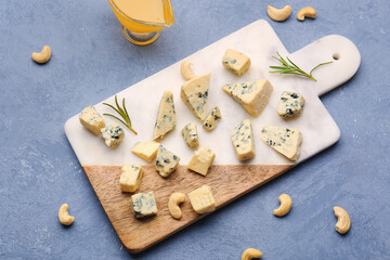 Board with pieces of tasty cheese on grey background