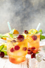 Iced refreshment drink orange cherry cola lemonade or mojito cocktail in glass on a wooden table. Fresh summer drink. Copy space.