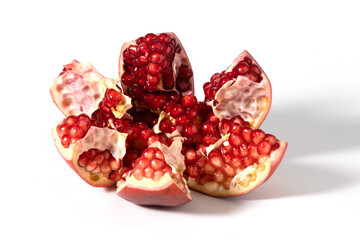 The fruit of the pomegranate is shown broken into pieces on a white background.