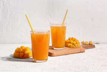 Glasses of fresh mango smoothie on light background