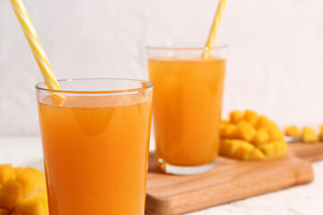 Glasses of fresh mango smoothie on light background, closeup