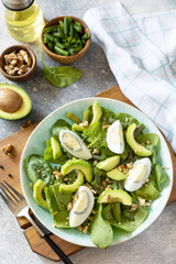Organic green avocado and spinach salad with eggs, green beans, nuts on a stone table. Healthy food, summer healthy eating.