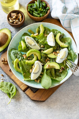 Healthy food, summer healthy eating. Organic green avocado and spinach salad with eggs, green beans, nuts on a stone table.