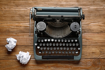 Vintage typewriter with crumpled paper on brown wooden background