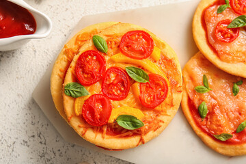 Board with different tasty mini pizzas on white background