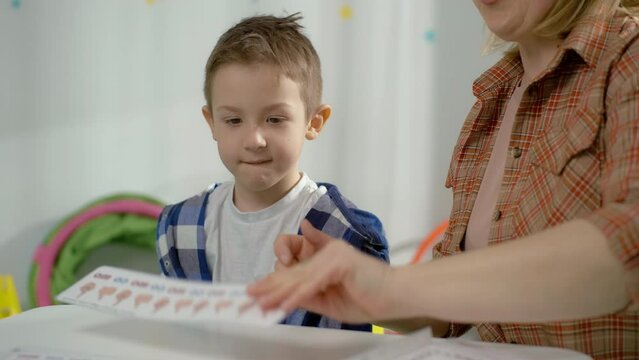 A Caucasian preschool boy works with a speech therapist. Training and classes with a teacher on the correct pronunciation of letters and sounds. High quality 4k footage