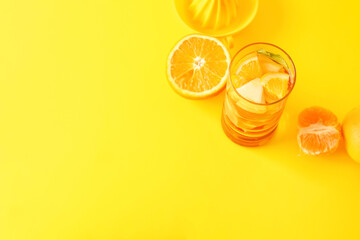Glass of infused water with different sliced fruits on yellow background