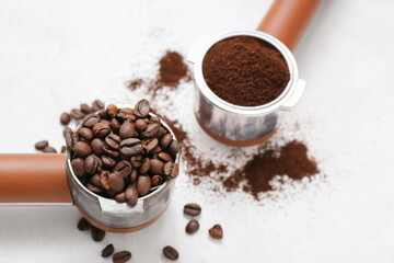 Portafilters with coffee beans and powder on light background