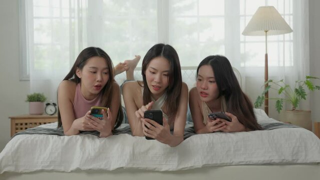 Group of Young Asian woman lying down on bed enjoy use a smartphone