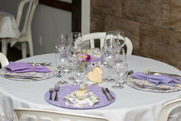 Mesa elegante com pratos decorados, rosas, flores, copos e taças de cristal
