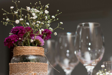 Mesa elegante com pratos decorados, rosas, flores, copos e taças de cristal