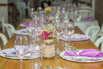 Mesa elegante com pratos decorados, rosas, flores, copos e taças de cristal