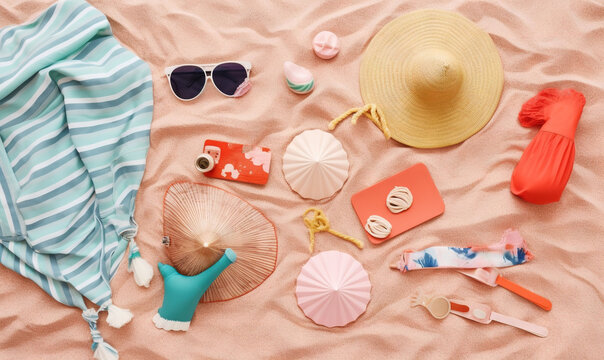 a beach towel, hat, sunglasses, and other items are laid out on the sand on a beach towel with a blue and white striped top.  generative ai