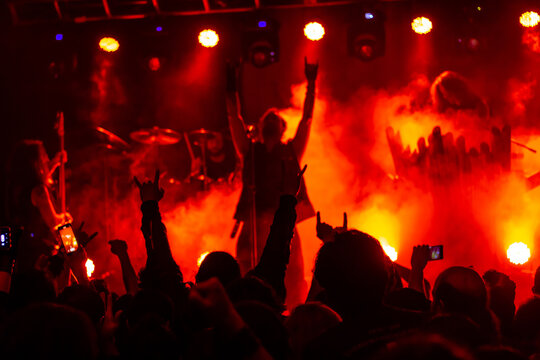 Concierto en vivo de Rock Metal, con publico enardecido, vibrando al son de la musica extrema. En un escenario con juego de luces, humo y sombras