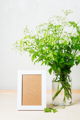 Cow parsley flowers in a glass jar and an empty picture frame.