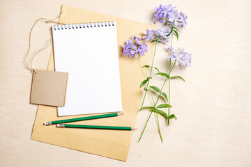 Mockup blank notebook, envelope, pencils and blue flowers.