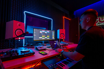 professional sound recording studio sound engineer or music producer sitting at the remote control mixing tracks on the screen neon light