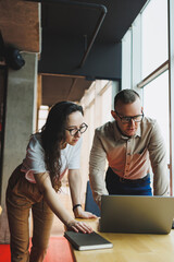 A young satisfied man talks to a female colleague and rejoices in the work done. Colleagues work at...