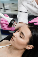 Thermal or radio frequency hardware RF lifting for smoothing wrinkles, improving skin tone and turgor. Tightening and rejuvenation of facial skin of girl at cosmetology procedure.