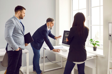 Team of businesspeople analyzing data using computer in office. Confident colleagues looking at computer screen discussing and analyzing financial data, brainstorming and communicating together