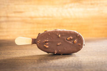 Popsicle, ice cream covered with chocolate on wooden table.