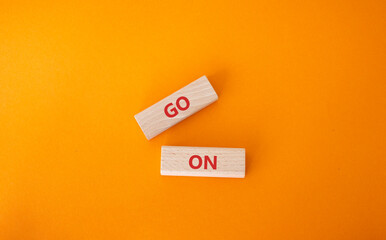 Go on symbol. Wooden blocks with words Go on. Beautiful orange background. Business and Go on concept. Copy space.