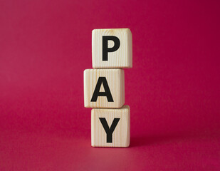 Payment symbol. Wooden cubes with words Pay. Beautiful red background. Business and Pay concept. Copy space.