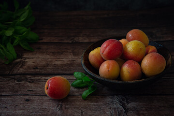 Fresh orange apricots on wooden table with dark background