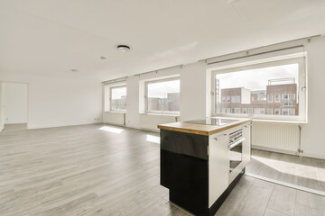 an empty living room with wood flooring and white walls, there is a large kitchen island in the corner
