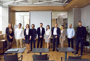 Group portrait of diverse, friendly and successful business team in loft coworking. Multiracial men and women stand together in row looking at camera. Concept of teamwork, business and partnership.