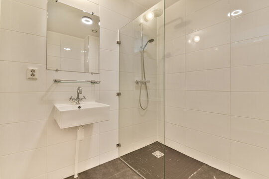 a modern bathroom with white tiles and marble flooring, including a glass shower stall on the right hand side