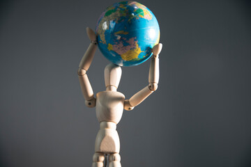 wooden mannequin with world on his hand