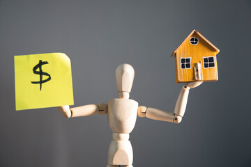 wooden mannequin with dollar and house