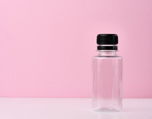 Empty plastic bottle with black cap on pink background