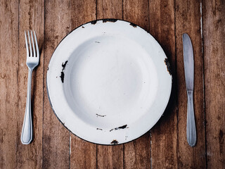 rustic empty plate demonstrating hunger on wooden background.
