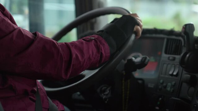 4K footage of bus driver with gloved hand in daylight. Driver holding steering wheel stock video.