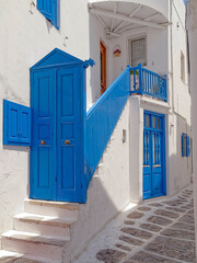 Bright blue painted wooden doors and stairs of a traditional house with white-washed walls . Travel to Mykonos island, Greece.
