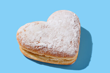 Heart shaped donut with glaze on blue pastel background