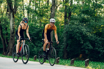 Couple riding bicycles outside of the city and wearing helmets and sunglasses