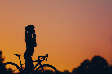 Obraz premium Silhouette of a woman riding a bike during a sport cycling race on a sunset