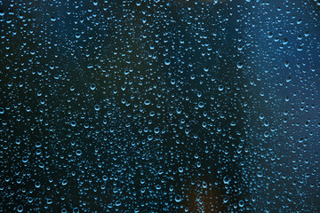 Naklejka na ściany i meble Rain drops on glass surface as background. Dark blue abstract backdrop. Selective focus.