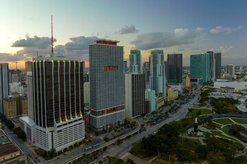 Obraz premium Aerial view of downtown district of of Miami Brickell in Florida, USA at sunset. High skyscraper buildings and street with cars and Metrorail traffic in modern american midtown