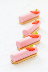 Vegan Strawberry cream cake of cylindrical shape, dessert bar. On cookies. Decorated with a fresh slice of strawberries. White background