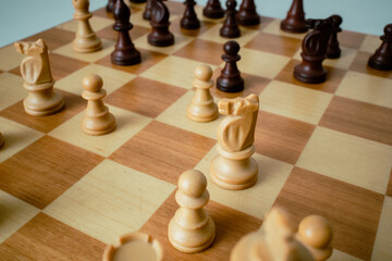 closeup photo of the chess board. Chess board on the round white table. Chess pieces lined up on...
