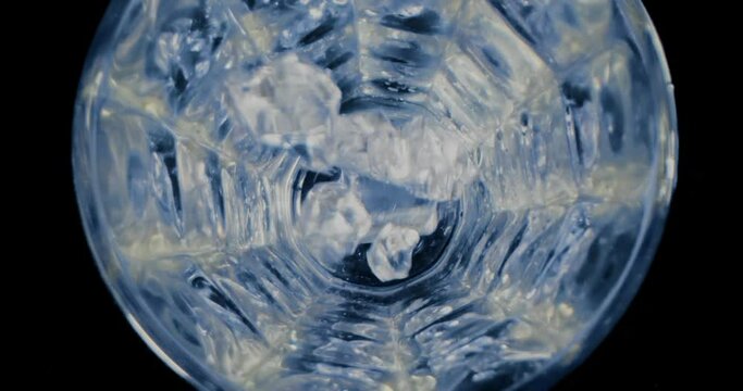 Ice cupe falling into a glass. Top view close up.